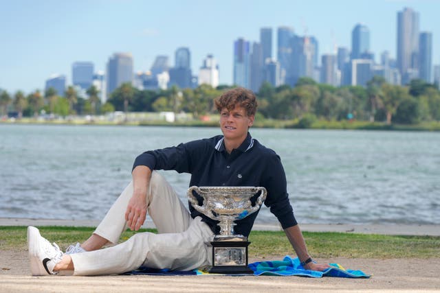 Jannik Sinner poses with Norman Brookes Challenge Cup in front of the Melbourne skyline (Mark Baker/AP)