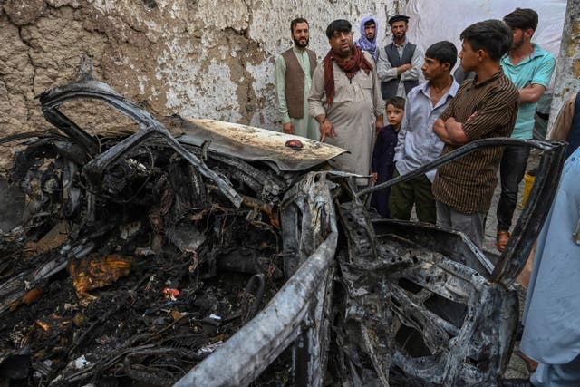 <p>Afghan residents and family members of the victims gather next to a damaged vehicle inside a house, day after a US drone airstrike in Kabul on August 30, 2021</p>