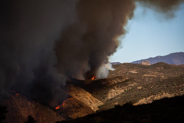 <p>Flames race up a hill as smoke from the Hughes fire fills the sky in Castaic, California, on Wednesday. After weeks of devastating fires and months without rain, the region is finally seeing some relief. But, storms could bring dangerous debris flows in wildfire burn scar areas, officials warn </p>