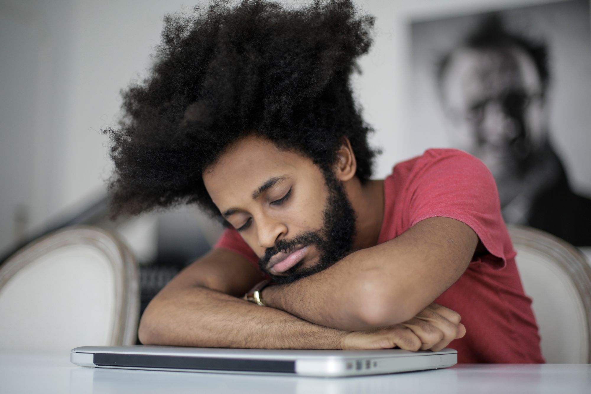 Man sleeping on laptop on desk.
