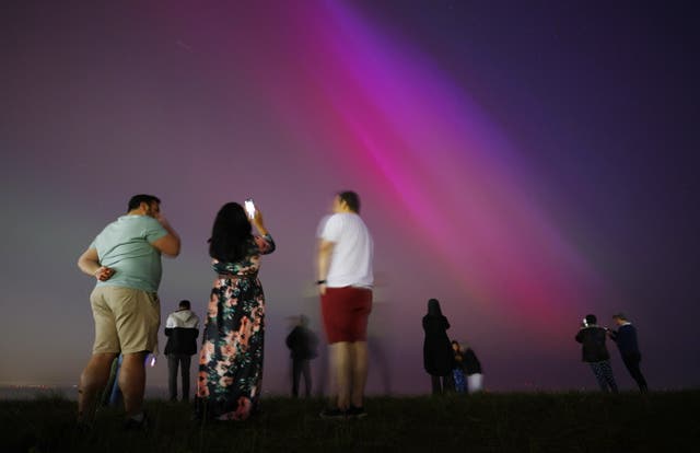 <p>People gather at Crosby Beach to look at the Aurora Borealis, also known as the Northern Lights, in Crosby</p>