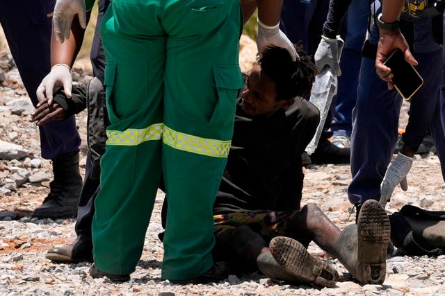 <p>A miner is assisted by rescue workers after being pulled from below ground</p>