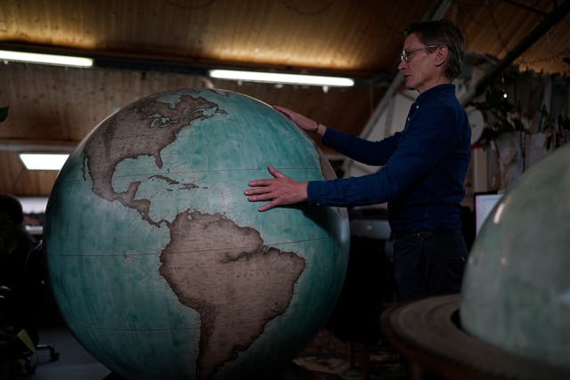<p>Peter Bellerby, the founder of Bellerby & Co. Globemakers, holds a globe at a studio in London</p>